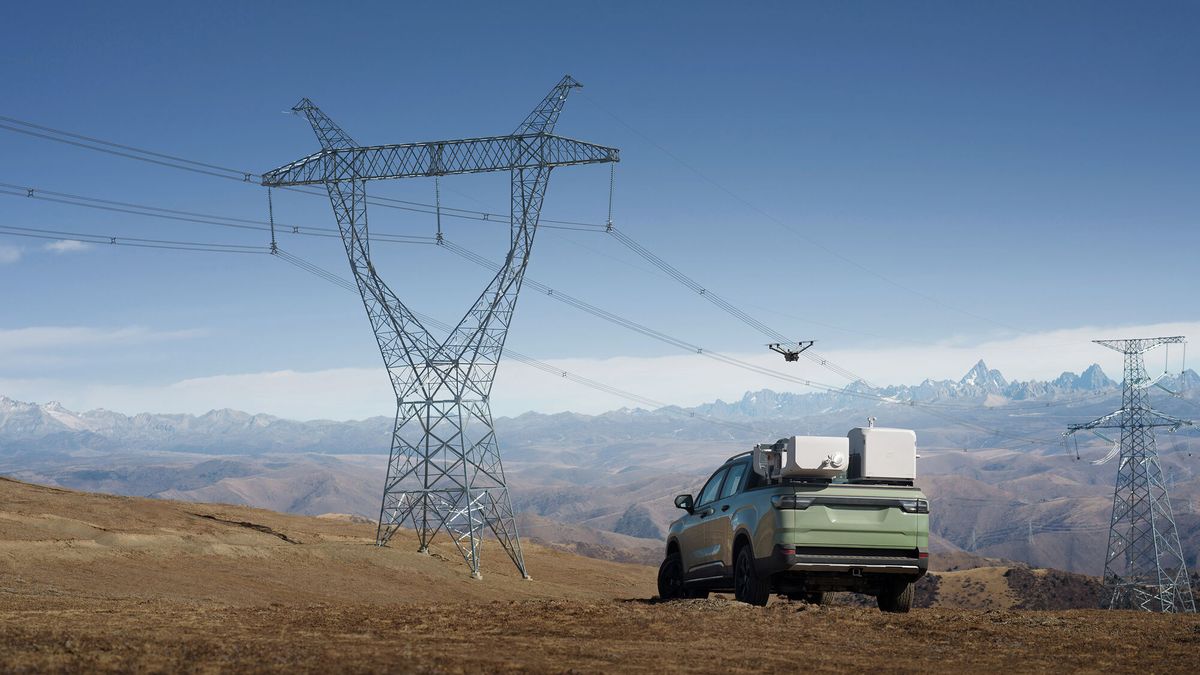 Drone inspecionando uma torre de transmissão de energia, com uma caminhonete e a estação de pouso ao lado